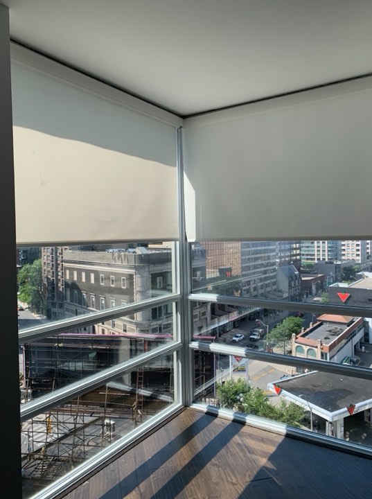 White roller shades on corner condo windows