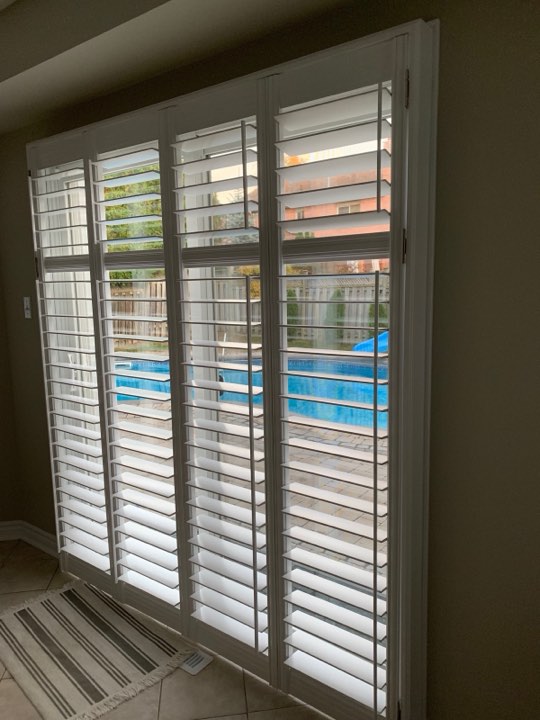 White shutters on a patio door facing a pool